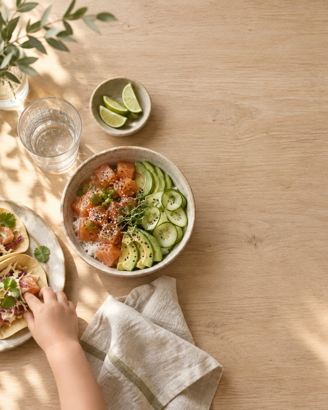 Ett bord med laxbowl, tacos och limeklyftor i eftermiddagsljus
